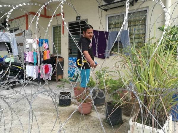 Jaidie menyiram pokok bunga di luar rumahnya yang sudah dipagar kawat berduri.