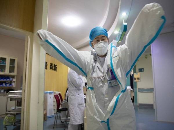 Zhang Jixian menyarungkan sut pelindung perubatan sebelum memasuki wad di hospital Wuhan, Provinsi Hubei, tengah China, pada 11 Mac 2020. (Foto: Ke Hao / Xinhua)