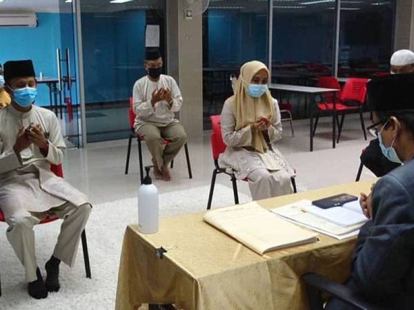 Pasangan pengantin mengaminka doa dibacakan oleh Mohd Nazri selepas pasangan pengantin selamat bernikah di Mini Auditorium Masjid Al-Azim, di Bukit Palah, di sini, hari ini.