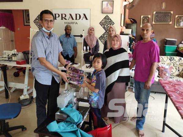 Saiful Yazan menyampaikan duit raya dan buah kurma kepada adik Nur Afia Qistina di rumahnya di Kampung Kepis Hilir, Johol.