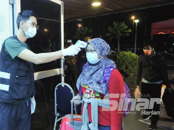 Kakitangan yang bertugas mengambil suhu pelajar akan di pusat pelepasan UKM, Bangi. - Foto Sinar Harian ASRIL ASWANDI SHUKOR dan ROSLI TALIB