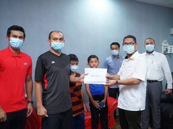 Ahmad Faizal (kanan) menyampaikan sumbangan kepada Mohd Nor yang sedang menjalani proses pemulihan akibat diserang angin ahmar di rumah bekas pemain itu, di sini hari ini. - Foto Facebook Ahmad Faizal