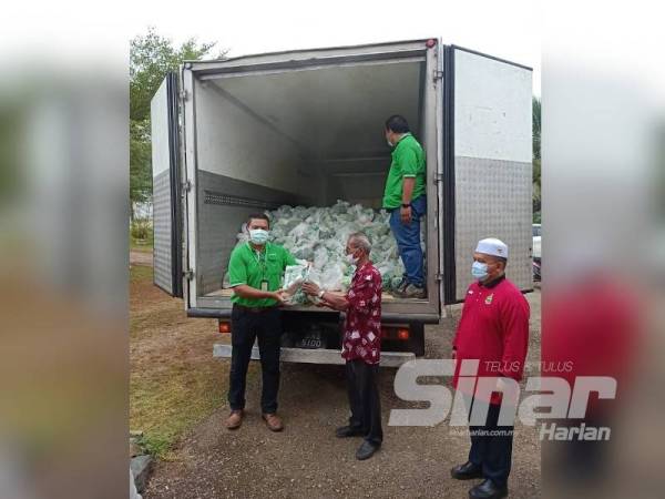 Azmi (kiri) membuat penyerahan simbolik pek bantuan kepada Yusof sambil diperhatikan Shahril Azman (kanan) di Felda Jengka 17 Khamis lalu.