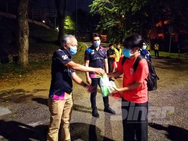 Muhammad Nasir (kiri) membekalkan makanan kepada pelajar yang berangkat pulang ke kampung malam ini.