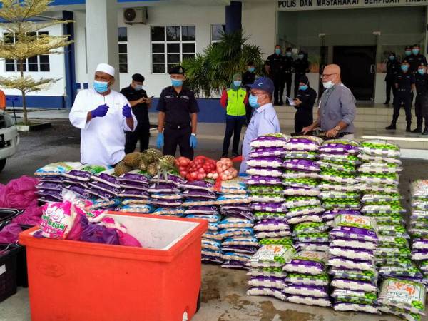 Isa (dua dari kanan) memantau penghantaran 300 pek Kombo Ramadan yang dibeli Abdul Azeez (kiri) untuk diagihkan kepada petugas barisan hadapan di Ibu Pejabat Polis Daerah Baling hari ini.