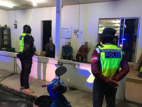 Anggota polis sedang menyoal siasat lelaki yang didapati menunaikan solat sunat tarawih di sebuah surau di Kijal, Chukai, di sini malam semalam. - Foto Ihsan IPD Kemaman