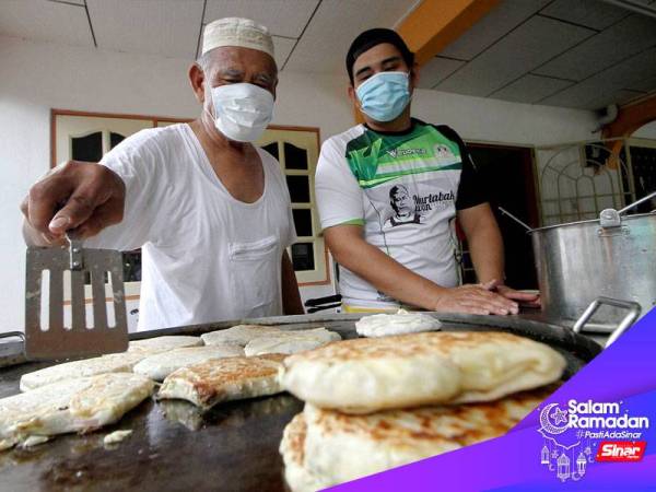 Muhamad Imran, 30, (kanan) membantu bapanya Mohd Ansop Mat Tasman, 72, menyediakan martabak yang dipesan pelanggan pada Ramadan ini di rumahnya Taman Desa Pakatan hari ini.