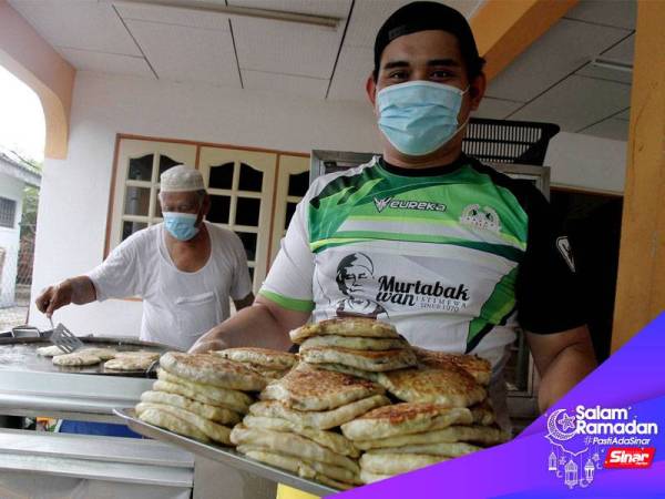 Peniaga Mohd Ansop Mat Tasman, 72, (kiri) dibantu anak bongsu lelakinya, Muhamad Imran, 30, memasak martabak yang dipesan pelanggan pada bulan Ramadan ini di rumahnya Taman Desa Pakatan hari ini.