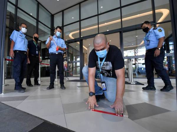 Pengurus Operasi dan Pengurusan Korporat KTCC Mall, Tengku Nurosmar Shah Tengku Abdullah (dua, kiri) melekatkan pita pelekat bagi tujuan penjarakan satu meter ketika tinjauan di KTCC Mall hari ini. - Foto Bernama