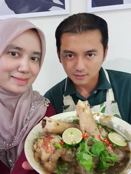 Nik Mohd Shahril Irwan bersama isterinya, Dr Farah Sabreena menunjukkan menu sup 'gearbox tok abah' yang menjadi pelengkap menu berbuka puasa mereka sekeluarga