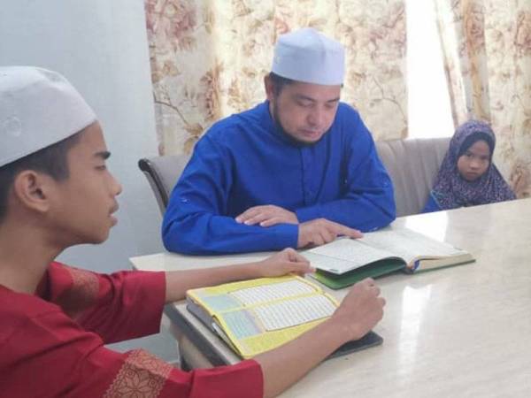 Mohd Khairul Azman (tengah) bersama anak sulungnya, Ahmad Al-Fateh, 16, membaca al-Quran. Turut kelihatan anak bongsunya, Hana Soffya Al-Kheir, 4.