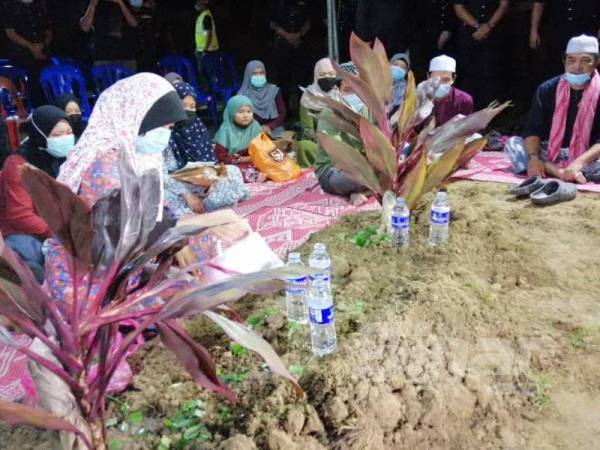Ibu Allahyarham, Norriza Mat Sani, 53, menyiram air di pusara anaknya. 