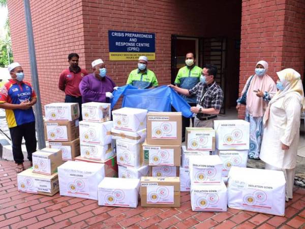 Abdullah (tiga dari kiri) menyerahkan gaun isolasi kepada Dr Redzuan sambil disaksikan Khairul Faizi (tengah) iaitu sumbangan Papisma Johor dan Khidmat Malaysia Johor di HSA, Johor Bahru di sini hari ini.