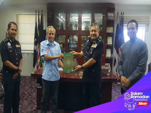 Muhammad Nasir (dua dari kiri) menyerahkan senaskhah al-Quran kepada Roslee (dua dari kanan) sebagai simbolik penyerahan al-Quran wakaf buat petugas PDRM. 