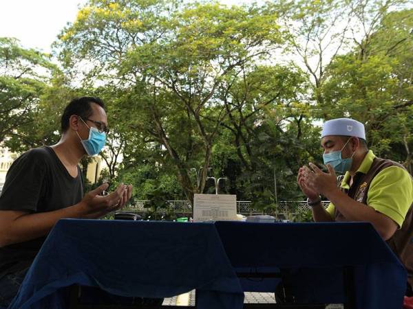 Amil Majlis Agama Islam Wilayah Persekutuan (MAIWP) Ahmad Samsuri Abdul Aziz (kanan) membacakan doa selepas selesai menerima wang zakat fitrah di pekarangan Masjid Negara hari ini.