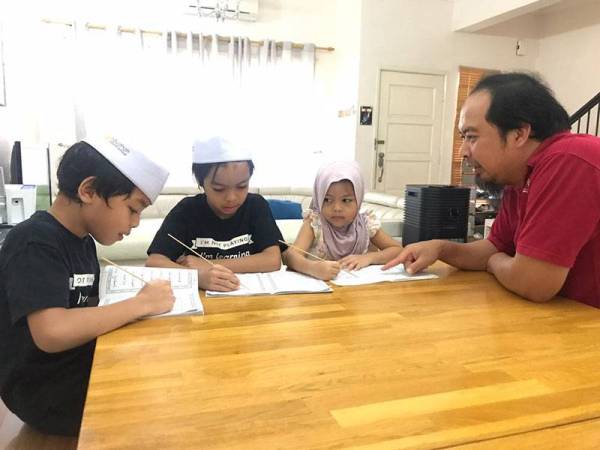 Ahmed Razman (kanan) melihat dan membantu anak-anaknya membaca Iqra' serta menghafal surah-surah lazim di rumah.
