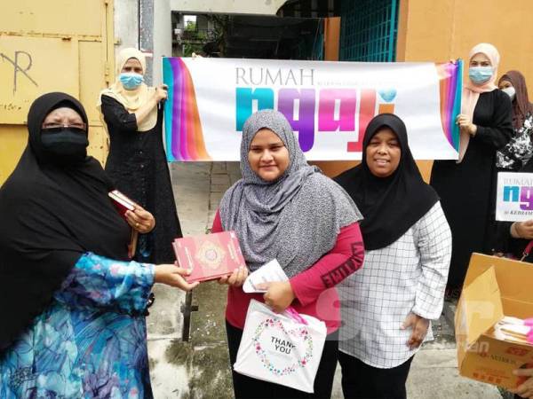 Wakil Rumah Ngaji Perak, Latipah Mohammad mengagihkan naskhah al-Quran yang diinfakkan penyumbang kepada penerima memerlukan di sini.