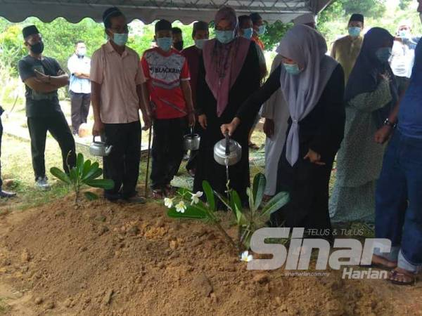 Ahli keluarga menyiram air di pusara Allahyarham Abu Bakar di Tanah Perkuburan Felda Chini 3.
