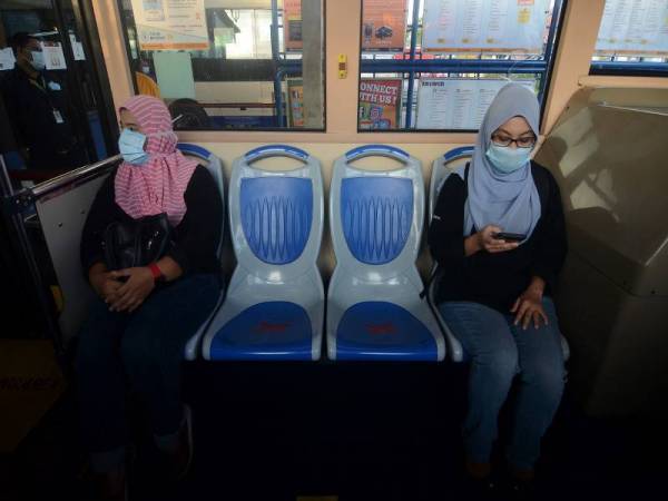 Penumpang Alisa Ali (kiri) dan rakannya Nurashikan Jamaludin mengamalkan penjarakan sosial semasa menaiki bas pada hari pertama Strategi Pemulihan Berperingkat Pulau Pinang hari ini. - Foto Bernama