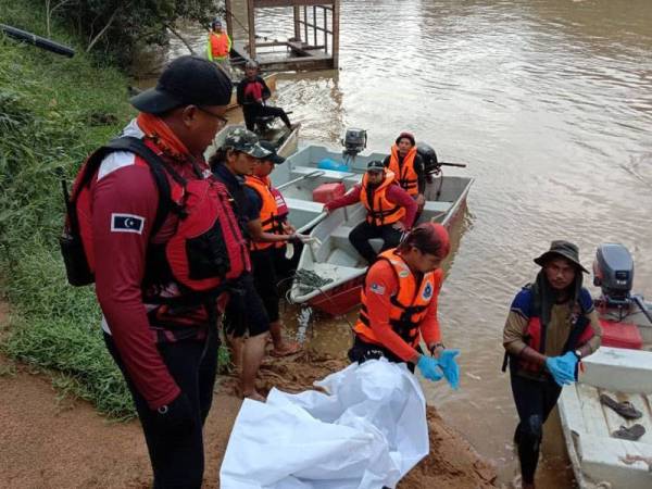 Mayat mangsa yang ditemukan tersangkut di tebing sungai di bawa naik ke darat oleh sepasukan anggota di lokasi (foto: Ihsan IPD Kemaman)
