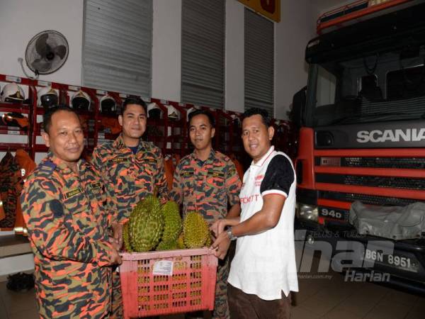 Muhamad Al Amin turut berkongsi rezeki dengan menyerahkan buah durian kepada Pegawai Bomba Kanan PBK II, Samsari Ibrahim (kiri) bersama anggotanya untuk berbuka puasa di Balai Bomba Pokok Sena.