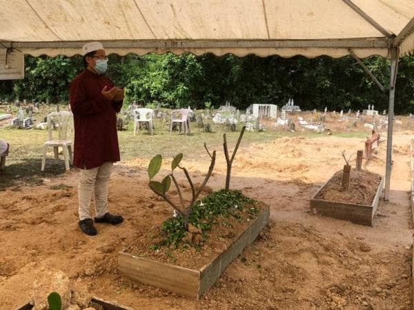 Kelihatan seorang lelaki berdoa di kubur Allahyarham Ismail.