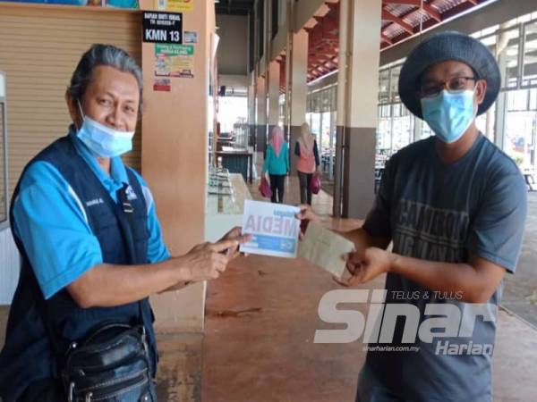 Khairul Azlam (kiri) menyampaikan bantuan kepada salah seorang pengamal media.