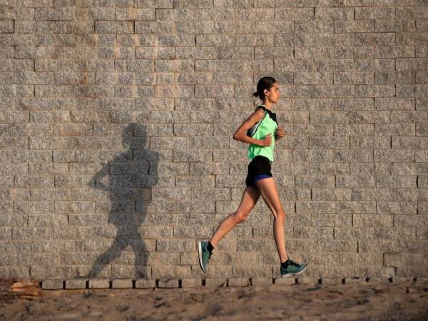 Seorang wanita berjoging di sepanjang pantai La Barceoneta yang mula dibuka hari ini. - AFP