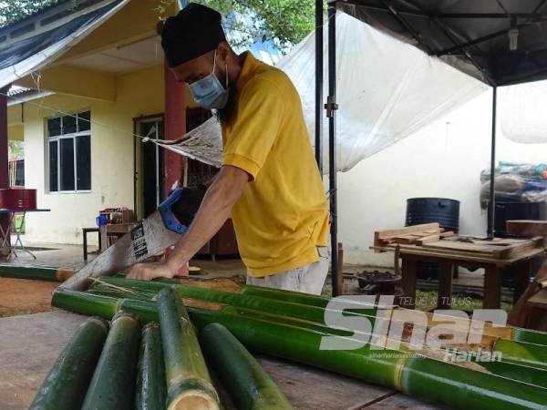 Nik Suhaimy memotong buluh untuk memasak lemang yang ditempah pelanggan.