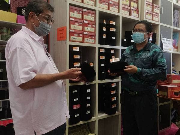 Mohamed Jalaludin (kiri) meninjau kedai Mohd Azhar (kanan) pada hari pertama pembukaan semula Kompleks Pekan Rabu di sini hari ini.