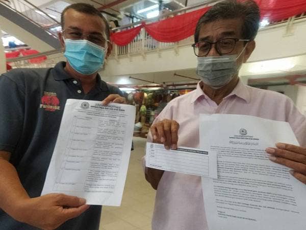 Mohamed Jalaludin (kanan) dan Pengurus Koperasi Pekan Rabu Alor Setar, Izahar Ibrahim (kiri) menunjukkan senarai SOP perlu dipatuhi peniaga.