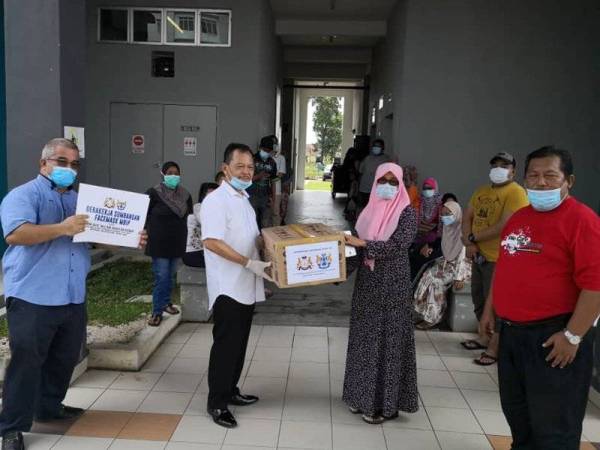 Abdul Rashid (dua dari kiri) menyampaikan sumbangan topeng muka kepada penduduk di Zon Perling.