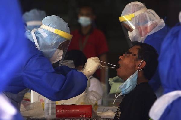 Petugas Kementerian Kesihatan Malaysia (KKM) mengambil sampel ketika menjalankan saringan Covid-19. Gambar hiasan
