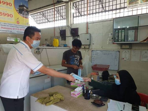 Kok Seong mengedarkan topeng muka kepada peniaga Pasar Besar Bahau.