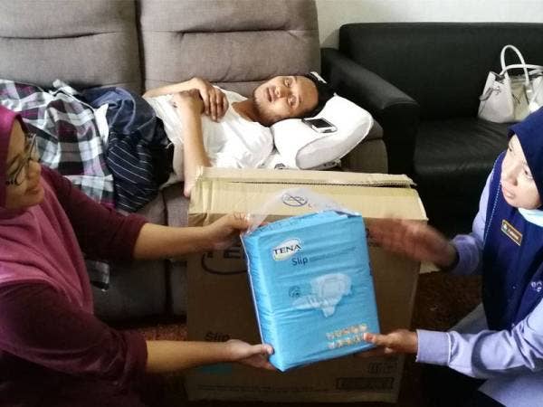 Farihah (kanan) menyerahkan bantuan pampers kepada isteri Azlan, Norhaspida.