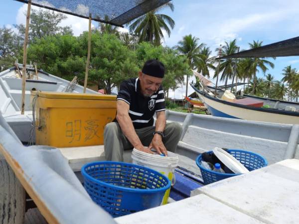 Mat Zahid sedang menyiapkan kelengkapan untuk aktiviti mencadat sotong petang ini di Jeti Nelayan Beserah hari ini.