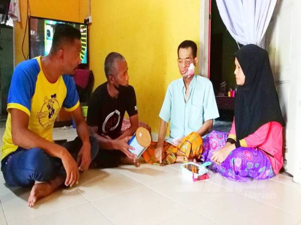 Mat Rofi (dua dari kanan) menerima kunjungan dari wakil Kelss di rumahnya di Kampung Kual.