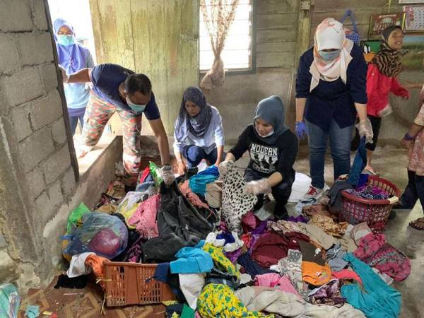 Sukarelawan membantu memilih pakaian yang diberi orang ramai yang masih diperlukan keluarga itu.