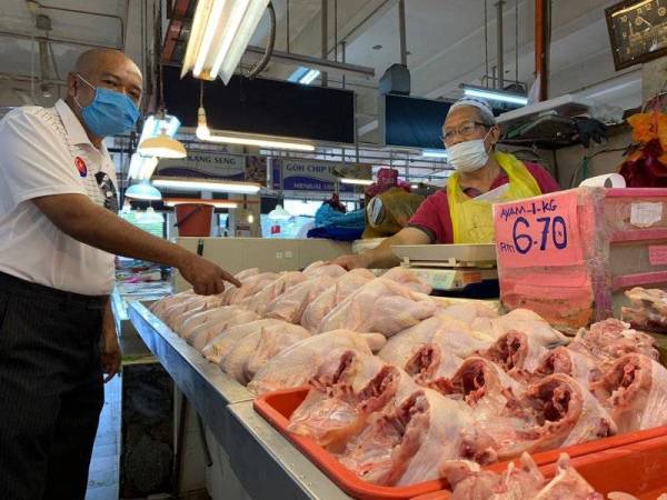 Abdullah Ideris (kanan) menunjukkan ayam segar yang dijualnya awal Ramadan lalu dengan harga RM6.70 sekilo, namun hari ini ayam dijual dengan harga RM8.40 sekilo di Pasar Awam Larkin, Johor Bahru, Johor.
