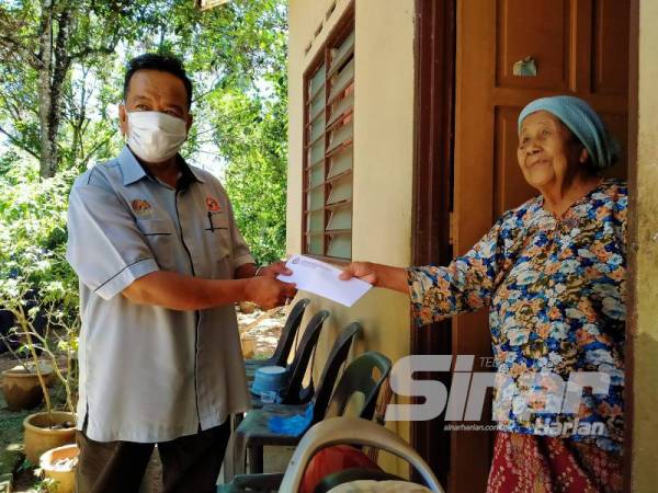 Peserta Ladang Sejahtera, Selasiah Saad, 82, dari Kampung Padang Ragut menerima dividen yang disampaikan Ahmad Shukri (kiri) kelmarin.