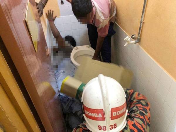 Anggota bomba cuba mengeluarkan mangsa yang tersepit dalam tandas rumahnya di sini hari ini.