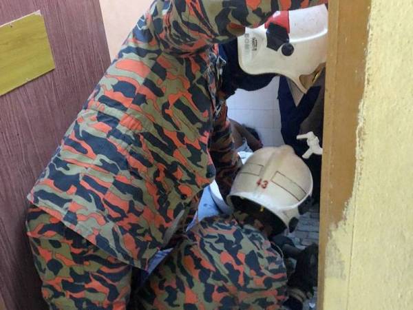 Anggota bomba cuba mengeluarkan mangsa yang tersepit dalam tandas rumahnya di sini hari ini.