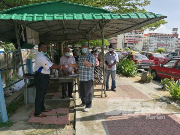 Ravichantar (kiri) menyampaikan sumbangan raya kepada salah seorang ahlinya hari ini.