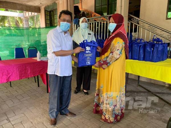 Che Abdullah (kiri) menyampaikan sumbangan Aidilfitri kepada salah seorang penerima di sini hari ini.