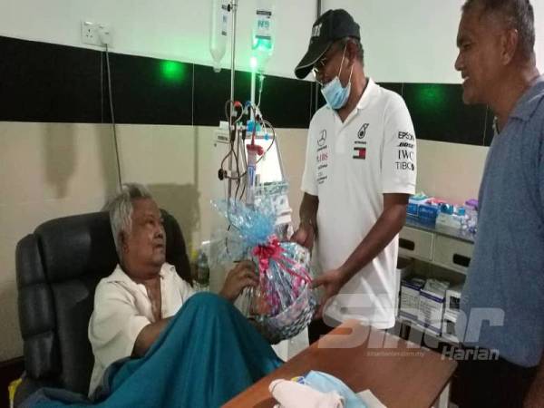Abdul Majid (kiri) menerima hamper daripada Nordin sambil diperhatikan Hanim di sebuah pusat dialisis di Kampung Gajah di sini hari ini. 