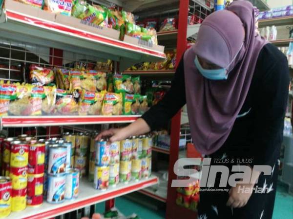 Norma menyusun barangan di kedai runcit tempat dia bekerja di Seksyen 15, Shah Alam semalam.