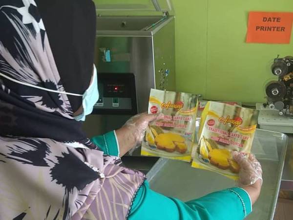 Hasanah memasukkan kuih bakar ke dalam plastik untuk pembungkusan.