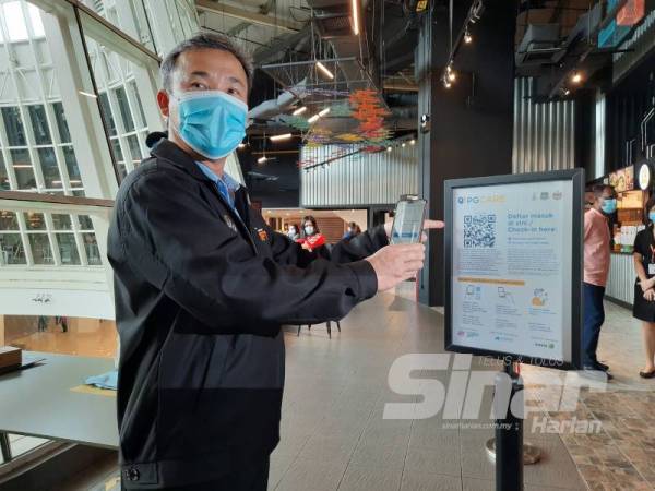 Tung Seang mencuba aplikasi PGCare di medan selera pasaraya Queensbay, Bayan Baru di sini hari ini.