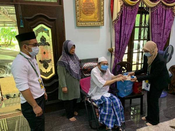 Hasnah (kanan) menyampaikan sumbangan I Medikel kepada Azman.