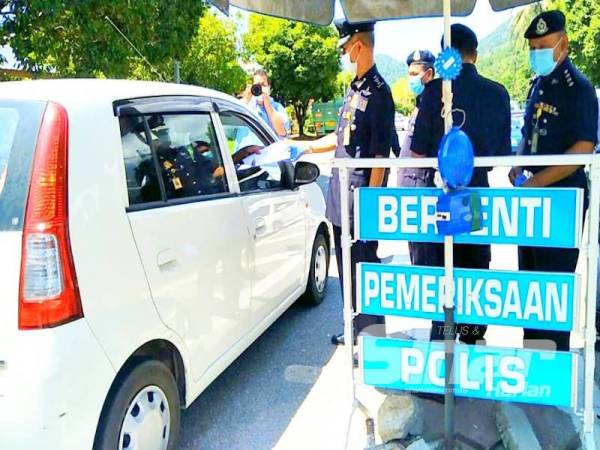 Hasanuddin (tiga dari kanan) memeriksa dokumen perjalanan pengguna yang melintasi sekatan jalan raya di Bukit Yong.